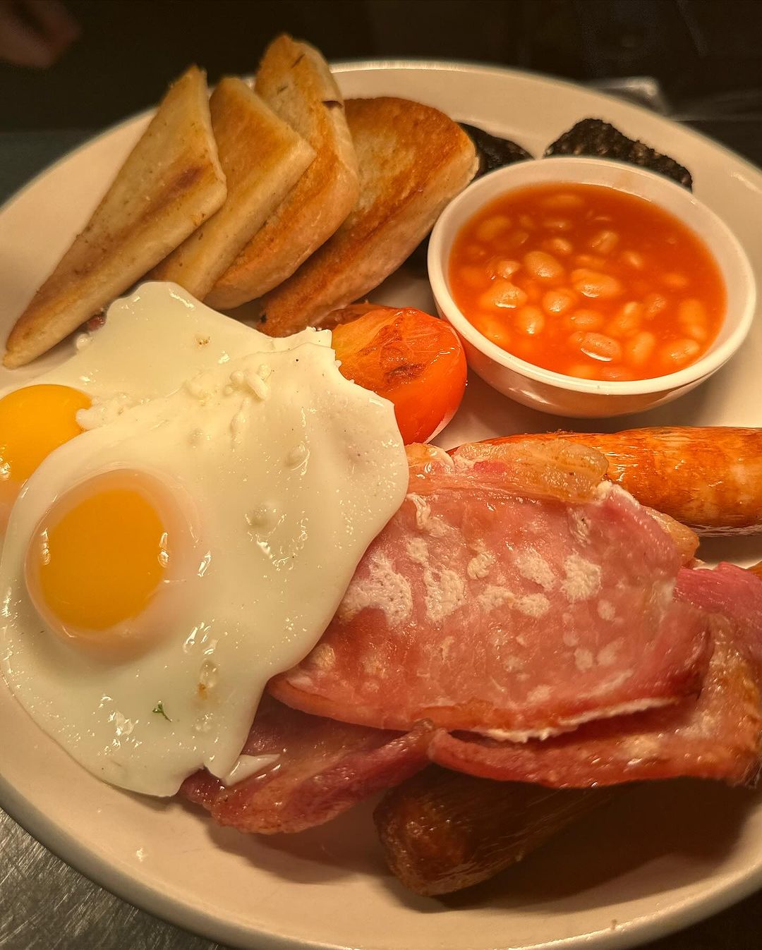 A full fry with bacon, sausage, egg, beans, toast and tomato