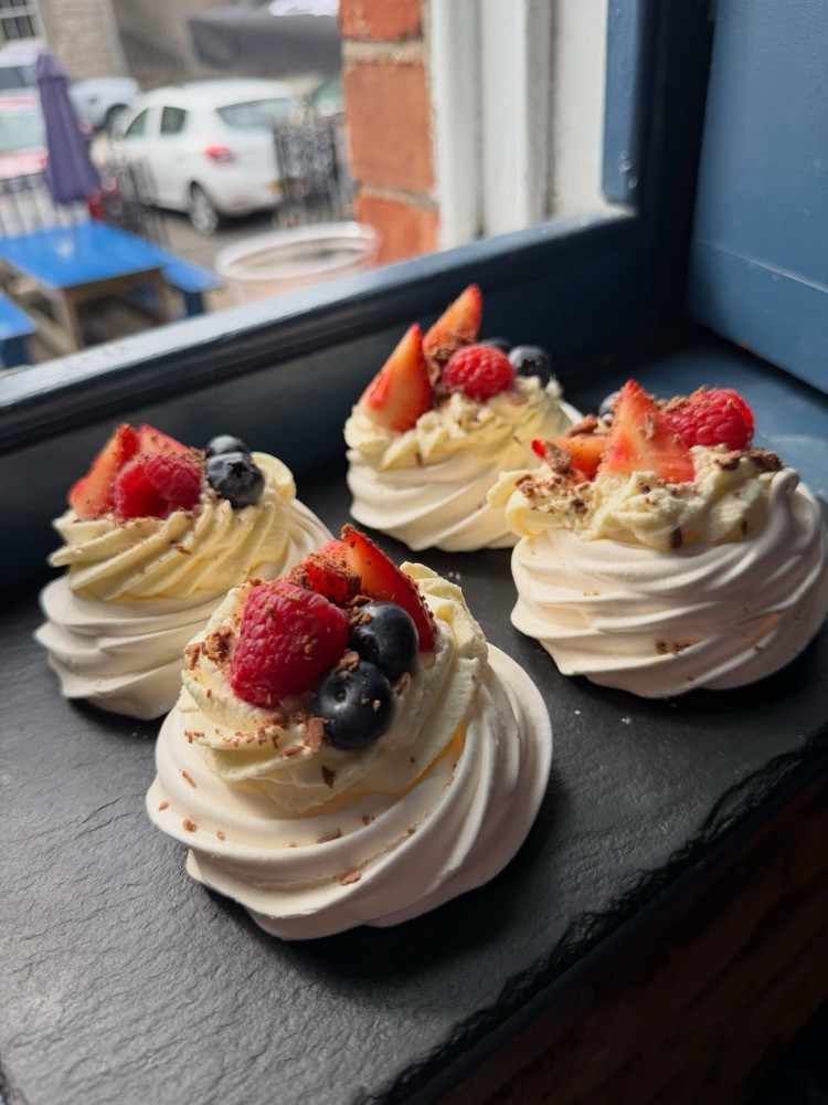 Fresh pavlova with strawberries and blueberries in the coffee house window